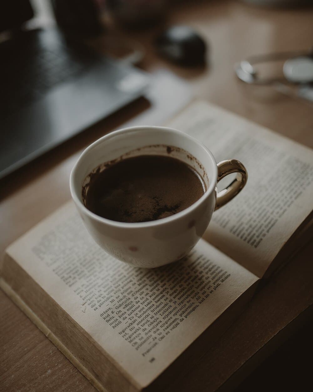 An open book and a cup of coffee in warm afternoon light